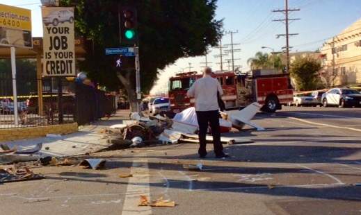 Street view of a crashed white plane and a fire engine in the background. 